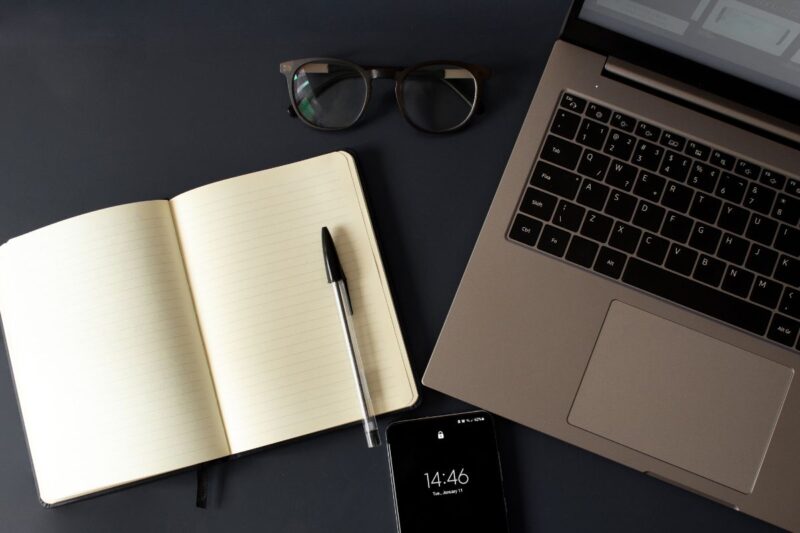 Materiais de estudo sobre finanças: livros, caderno e vídeo no celular.